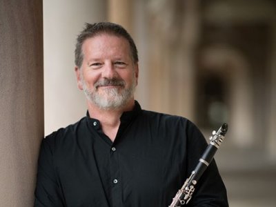 A man standing in a sandstone building holding a clarinet